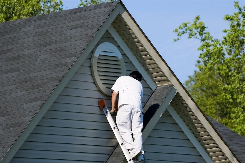 A man painting the exterior of a house